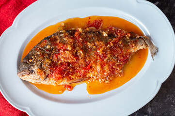 Two deep fried sea bream fish on a plate served with a sweet chilli, crush chilli and garlic sauce
