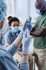 Nurse in protective gloves holding syringe with medicine during medical procedure at hospital