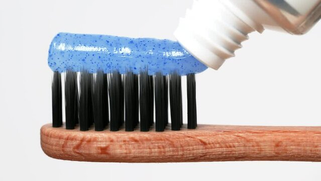 Macro view of toothpaste with toothbrush.Slider shot of toothpaste on white background.ecological toothbrush with beech wood handle and bristles with activated carbon.dental care.
