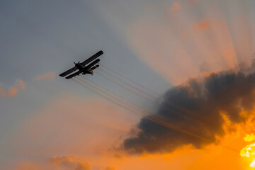 airplane in flight at sunset , air disinsection - crop duster