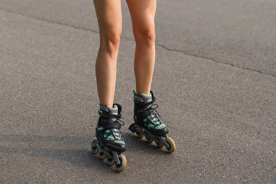 cropped image of legs of woman roller skating on asphalt road
