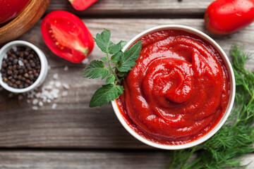 Homemade tomato sauce in white bowl, fresh tomatoes, spices and herbs. Top view. Close-up 