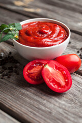 Homemade tomato sauce in white bowl, fresh tomatoes, spices and herbs. Food background