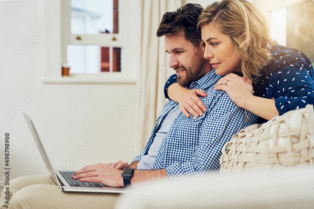 Poster browsing the internet together. shot of an attractive couple using a laptop together at home.