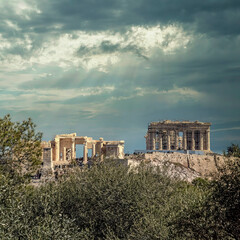 Fototapeta na wymiar Parthenon ancient Greek temple on Acropolis of Athens with olive trees foliage, under dramatic cloudy sky