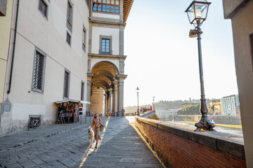 Street view on medieval town near Arno river in Florence on sunset. Woman walks with a dog. Wide...