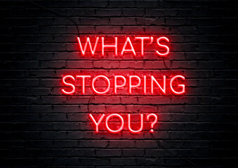 Red neon sign motivational quote with brick wall background. What's stopping you. 