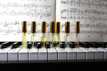 seven perfume aroma bottles with golden caps on piano keys on wooden classic piano with musical note