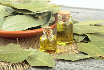 Natural bay laurel essential oil in glass bottles with dried leaves on a wooden table. Healthy...