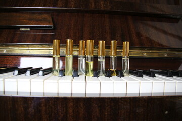 Seven perfume aroma bottles with golden caps on piano keys on wooden retro piano