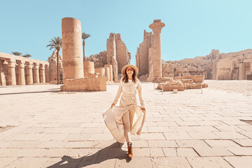 Happy woman traveler explores the ruins of the ancient Karnak temple in the heritage city of Luxor...