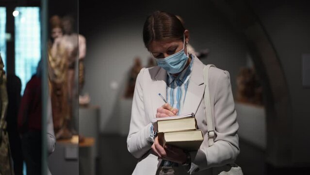 woman viitor at museum exhibition with book in hand