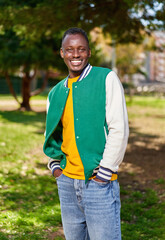 Portrait of happy afro man smiling outdoors during sunny day. Shot of african-american male looking at camera standing outside