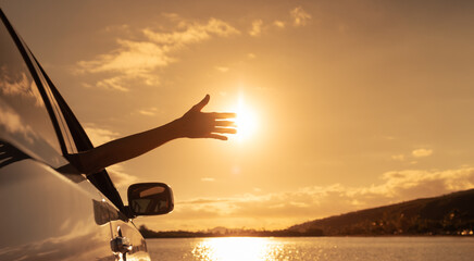 Feelings of happiness and joy. Happy woman sitting in car with hands up to the sunlight. 