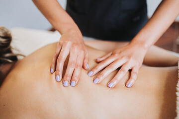 Unrecognizable therapist making back and spine massage to a female patient. Relaxing and de-stress