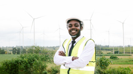 African engineer man stand front  wind turbines generating electricity power station. Concept of sustainability development by alternative energy