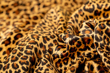 Satin fabric close up background and texture with place for text. Leopard print, silk orange.