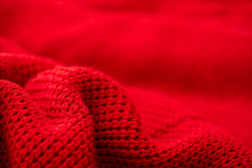 Knitted surface of woolen things as a background. Close-up of soft fabric red color knitted patterns texture. Warm winter clothing. Background textile surface with copy space for text.