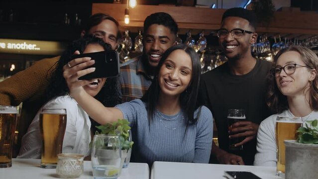 Multi-ethnic group of friends taking a selfie at a restaurant. 