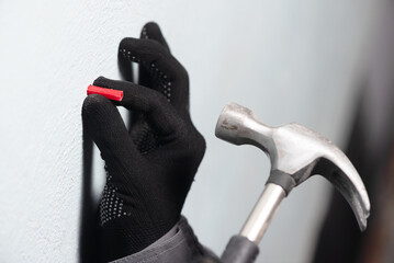 Worker inserts a plastic dowel into the wall close up. - obrazy, fototapety, plakaty