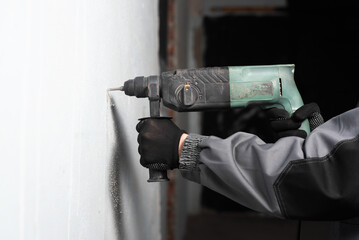 Worker is drilling the wall by the perforator close up.