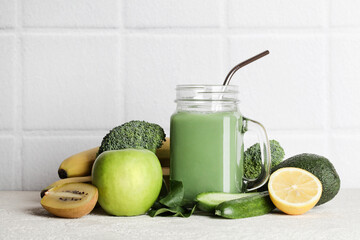 fresh green smoothie in glass bottle with vegetables on white ceramic tile background.vegan food, self care and healthy lifestyle.Healthy detox diet