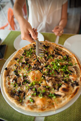 People hands taking slices of pizza. Table with pizza in a restaurant. Pizza and hands close up on a green