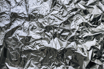 Abstract background, texture of silvery shiny foil, colored crumpled old paper for packing goods. Closeup photo, top view, copy space.