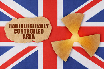 On the flag of UK, the symbol of radioactivity and torn cardboard with the inscription - Radiologically controlled area