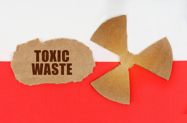 On the flag of Poland, the symbol of radioactivity and torn cardboard with the inscription - Toxic...