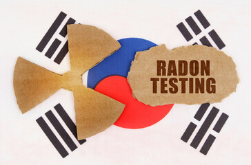 On the flag of South Korea, the symbol of radioactivity and torn cardboard with the inscription - Radon Testing