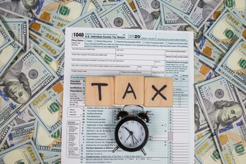 tax form 1040 on dollar background. The word tax on cubes.