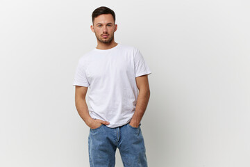 Serious sexy tanned handsome man in basic t-shirt hold hands on pocket posing isolated on over white studio background. Copy space Banner Mockup. People emotions Lifestyle concept. Model snaps
