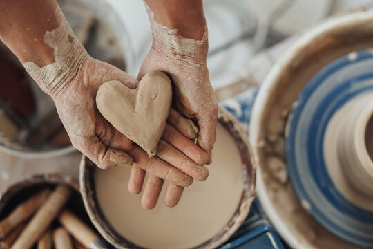 Flat Lay of Pottery Master Holding a Heart Crafted from Clay, Handmade Work