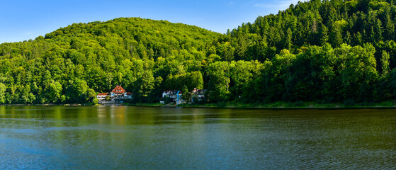 Lake Bystrzyckie located in a mountain valley, green forest on the slopes of the mountains, the view from the lake shore on a sunny summer day.
