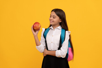 Happy kid smile holding apple and school bag yellow background, back-to-school