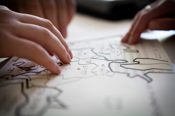 A blind or visually impaired pupil revises the maps in relief to pass. - obrazy, fototapety, plakaty
