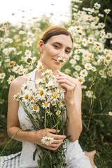 a girl with a big bouquet of daisies sits on the field