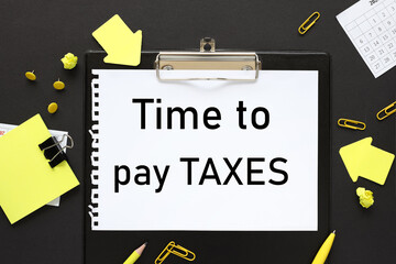 Time to pay taxes. text on boom on folder on black background