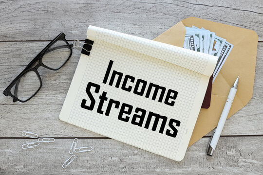 INCOME STREAMS - text on an open notebook on an envelope with money. near black glasses