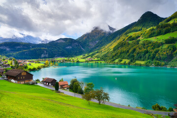 Lungern, canton of Obwalden, Switzerland. A view of rural homes in a green meadow. A lake in a mountain valley. A popular place to travel.