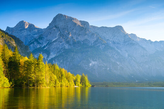 High mountains and reflection on the surface of the lake. The forest near the water. Landscape in the highlands in the summertime. Photo in high resolution.