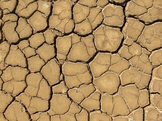 Cracked dry earth. There are deep cracks on its surface. Dry weather gives a beautiful pattern on the surface of the earth.