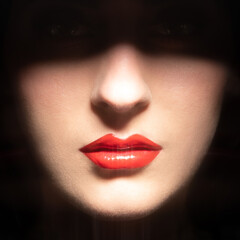 Beauty, fashion, make-up concept. Part of woman face hides in black shadow. Visible red sexy sparkling lips, nose and cheeks. Lips is in camera focus