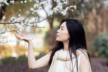 Candid lifestyle Portrait of happy young beautiful asian sexy woman enjoying life outdoor in park at spring. Smiling millennial girl with perfect clear glow skin and long brunette hair