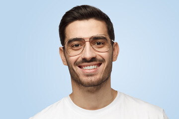 Fototapeta premium Young smiling handsome man in glasses and t-shirt isolated on light gray background