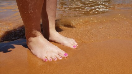 Bare feet with a pedicure on a beach vacation