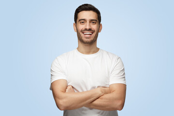 Young attractive European Caucasian man with arms crossed smiling and laughing
