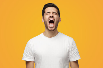 Young man standing with eyes shut and mouth open as if screaming in despair