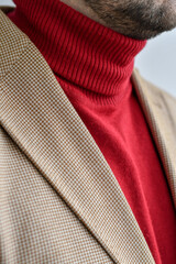 Detail of men outwear, light beige blazer combined with red sweater. Selective focus.